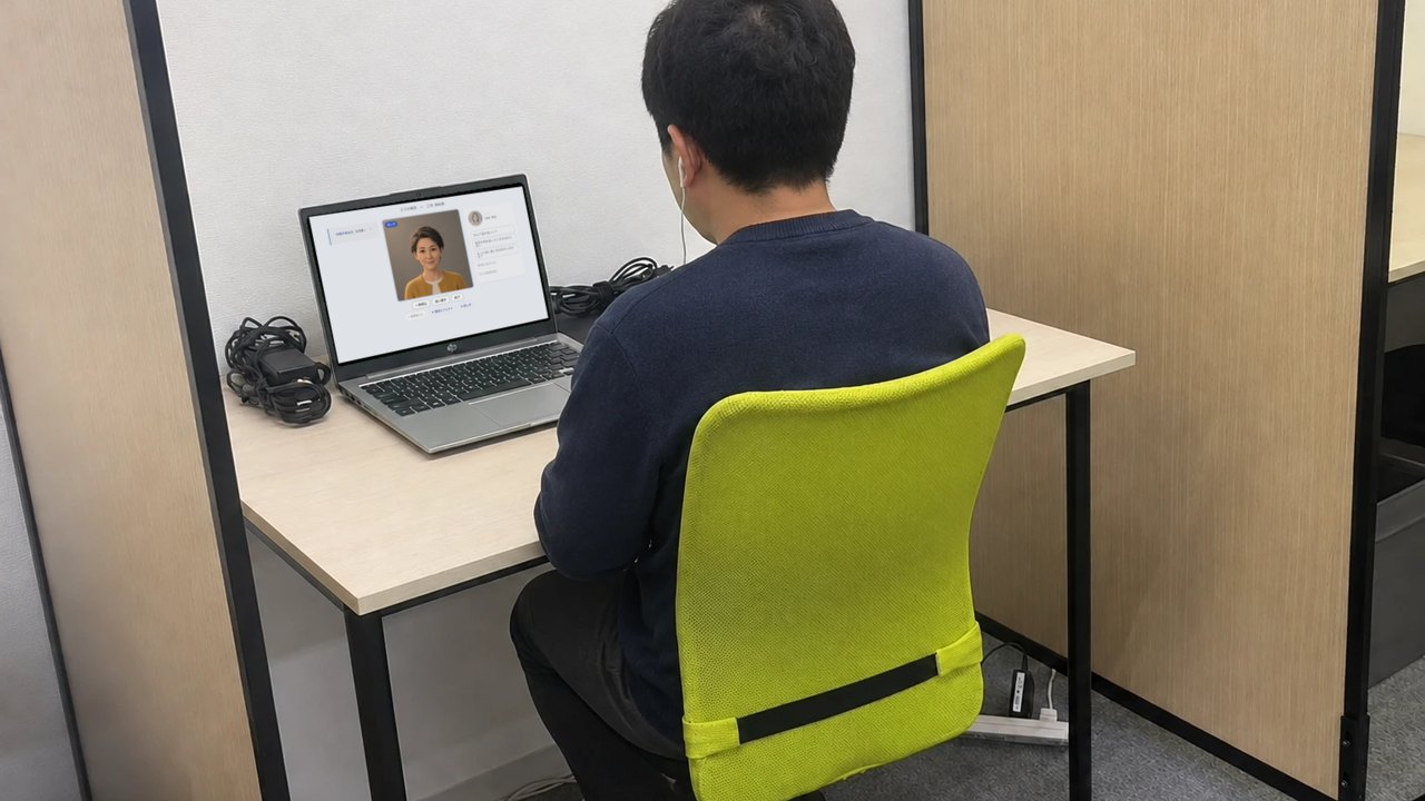 仕切りのある1人ずつの席。利用者がイヤホンをつけて、ノートパソコンでAIと練習している